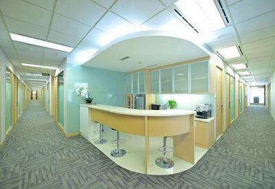Modern office breakout area with a curved wooden coffee bar and high stools.
