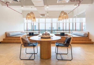 Casual breakout area with tiered wooden seating, round tables, and woven pendant lights.