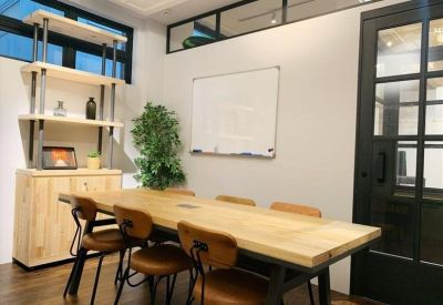 Bright meeting room with a large wooden table, leather chairs, and a whiteboard.