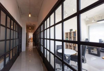 Bright corridor featuring industrial glass partitions leading to a meeting room.
