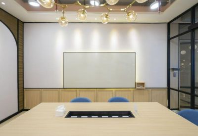 Minimalist meeting room with a large light-wood conference table and a built-in whiteboard wall.