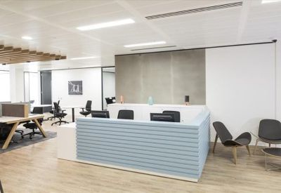 Bright reception desk with a light blue textured front and modern lounge chairs.