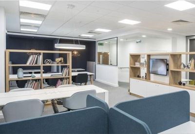 Open-plan coworking space with white desks and wooden divider shelves.