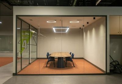 Modern lobby area with glass-partitioned rooms and a minimalist wood table.