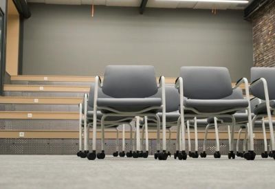 Rows of modern grey task chairs with wooden steps in the background.