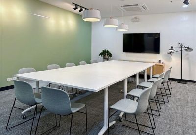 Spacious meeting room with white table and green feature wall.
