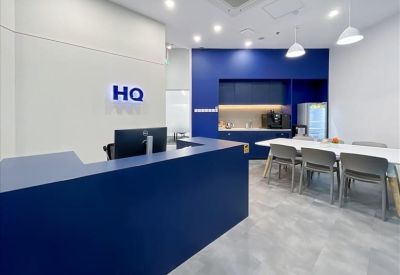 Bright reception and lounge area with a blue desk and kitchenette.
