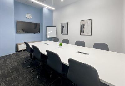 Spacious meeting room with a long white table and a flat-screen TV.