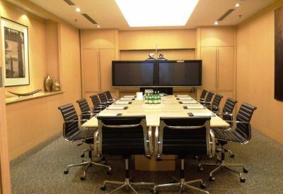 Professional boardroom with a large conference table, leather chairs, and integrated presentation screens.