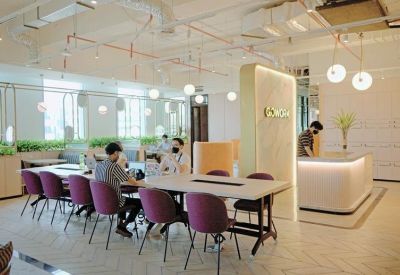 Bright reception area featuring a curved white desk and a large collaborative workspace.