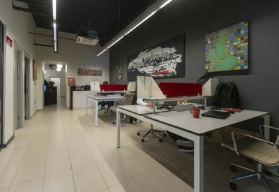 Open-plan office space featuring white desks and vibrant wall art.