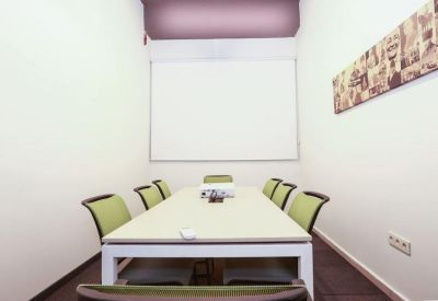 Bright meeting room with a white conference table and green chairs.