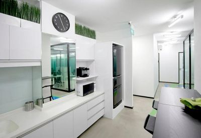 Communal kitchen and breakout area with white cabinetry, coffee machine, and wall-mounted clock.