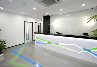 Bright reception area with a modern desk featuring blue and green geometric light accents.