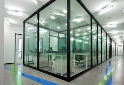 Bright office suite with rows of desks, ergonomic chairs, and large windows overlooking greenery.