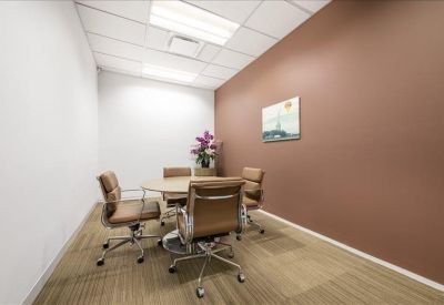 Private four-person office suite with a round table and warm brown accent wall.