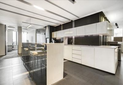 Modern office kitchen and breakout area with white cabinetry and a high breakfast bar.