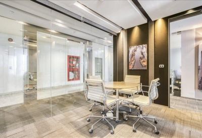 Small meeting room with glass walls, a round table, and white leather chairs.