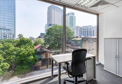 Private window office with a view of city greenery and a sleek desk.