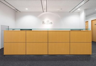 Reception area with a modern wood-paneled front desk and a backlit logo on the wall.