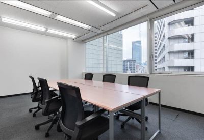 A professional boardroom with a long wooden table and ergonomic chairs.
