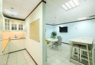 Bright communal kitchen and breakout area with white dining tables and a TV.