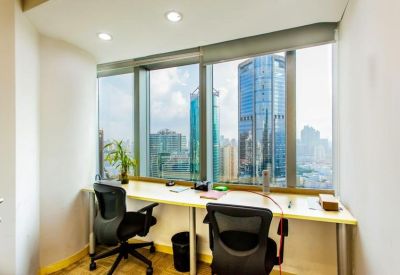 Sunlit office workspace featuring a long desk facing a window with city views.