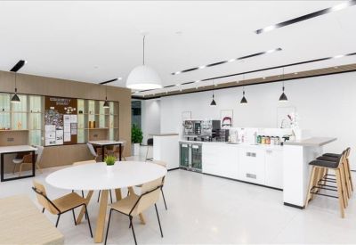 Sleek communal kitchen and dining area with a round white table, breakfast bar, and coffee station.