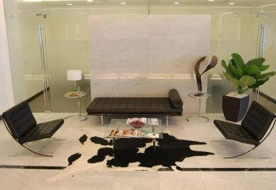 Contemporary lounge area featuring black leather chairs and a cowhide rug.