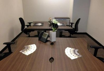 Collaborative office workspace with shared wooden desks and ergonomic chairs.