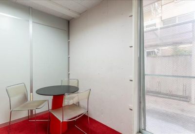 Sunlit communal area with a cafe-style table and red carpet flooring.