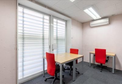 Two-person private office with light wood desks and vibrant red chairs.
