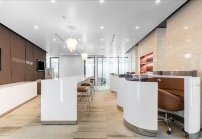 Bright business lounge with a sleek white breakfast bar and private work pods.
