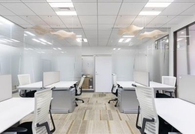 Spacious open-plan coworking area with white desks and glass partitions.