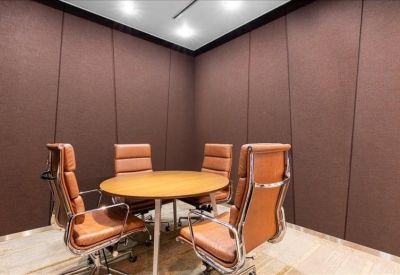 Small meeting room with a round table, four leather chairs, and brown acoustic wall panels.