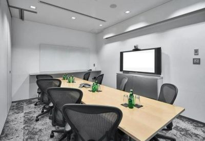 Sleek meeting room featuring a long wooden table, ergonomic chairs, and a large video conferencing screen.