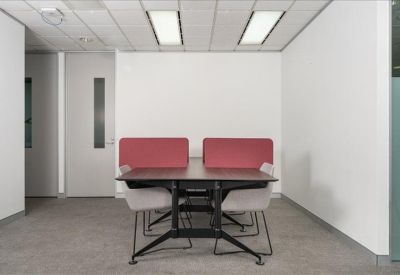 Four-person collaborative table with red privacy screens and grey upholstered chairs.