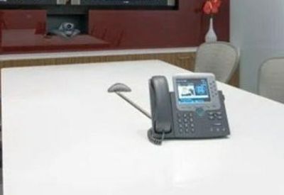 Meeting room with a white conference table, grey mesh chairs, and a built-in conference phone.