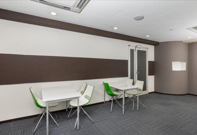 Bright coworking area with white tables and vibrant green accent chairs.