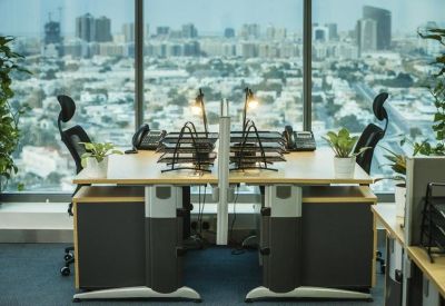 Symmetrical bank of workstations with city views through floor-to-ceiling windows.