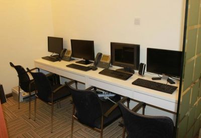 Shared office space with four computer workstations and black mesh chairs.