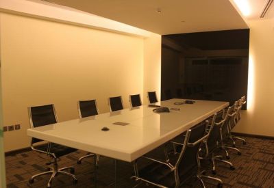 Meeting room with a long white conference table and black executive chairs.