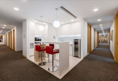 Modern communal break area with a white bar counter and red high-top stools.
