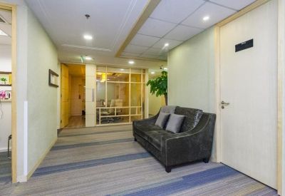 Breakout corridor with a dark grey sofa and glass-walled meeting rooms.