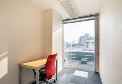 Small private office suite featuring a desk with a vibrant red ergonomic chair.