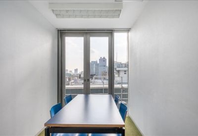 Bright private meeting room with a dark wood table and blue chairs overlooking city views.