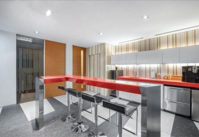 Modern breakout kitchen area featuring a vibrant red breakfast bar and stools.