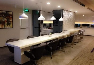 Modern communal break area with long white counter and designer black chairs.