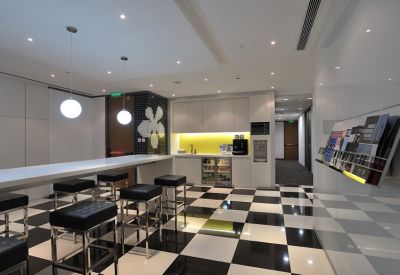 Modern communal breakout area with checkerboard flooring, a white breakfast bar, and a yellow feature backsplash.