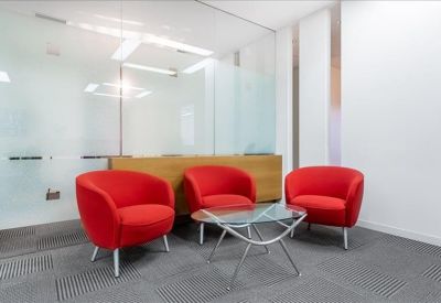 Modern lounge area featuring bright red armchairs and a glass coffee table.